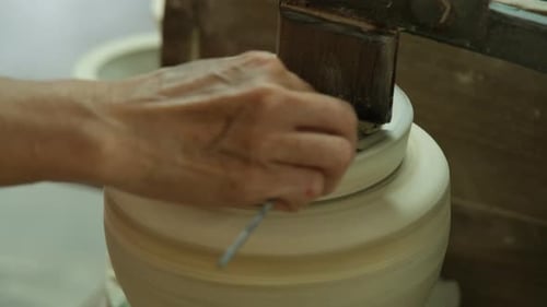 Gros plan d'une femme travaillant sur un tour de potier fabriquant des objets en argile dans un atelier de poterie.