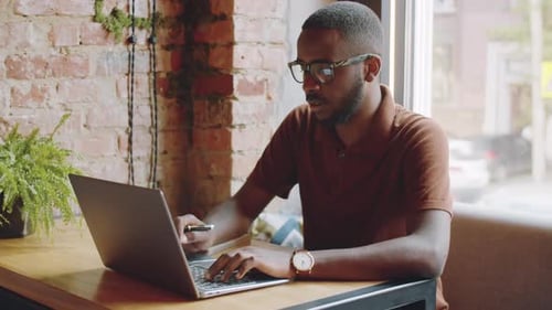 Cheerful Afro-American Man Using Laptop in Cafe