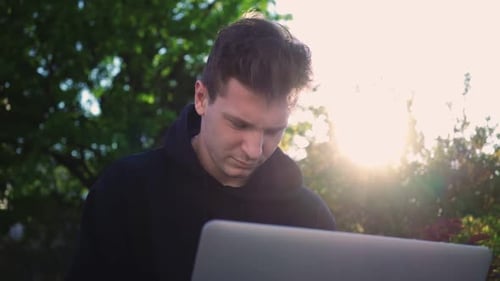 Guy Works at Laptop in City Park