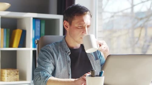 Young male entrepreneur works at home office at the computer.