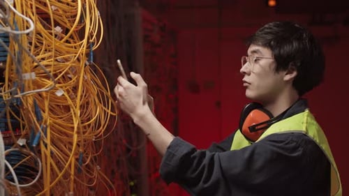 IT Administrator Making Photo of Wires in Data Center