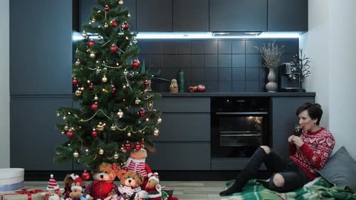 Woman Enjoying a Drink Beside Christmas Tree
