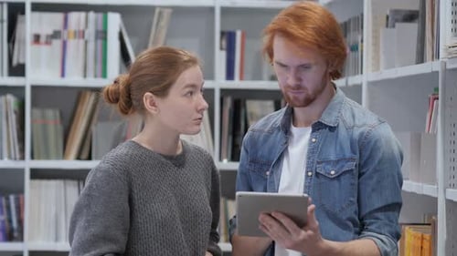 Jeunes coéquipiers : étudiants naviguant sur tablette PC dans le cadre de travaux de bibliothèque