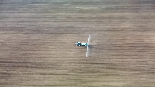 Tractor de vista aérea rociando semillas en campo terrestre