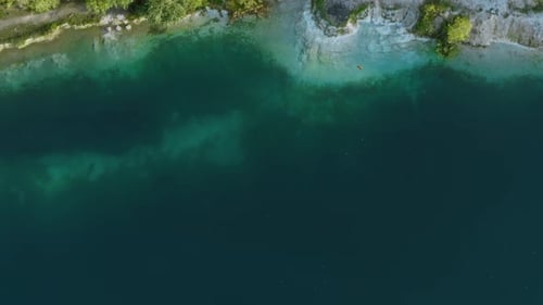 Aerial Top Down Flight Over Amazing Deep Lake Surrounded By Green Forest. Beautiful Lakeshore, Clean