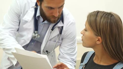 Doctor Consults With Young Woman About Paperwork