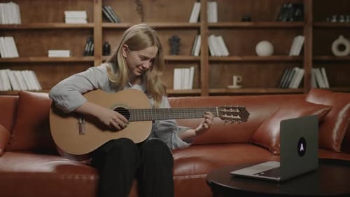 Woman Playing Acoustic Guitar on Couch Indoors