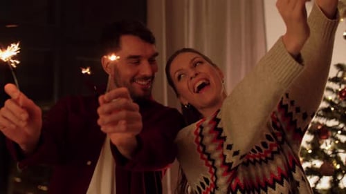 Happy Couple Holds Sparklers by Christmas Tree