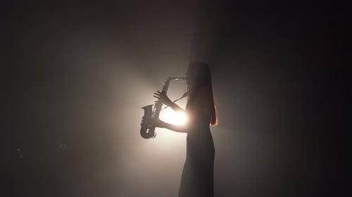 Silhouette of Woman Playing Saxophone in Dark Room