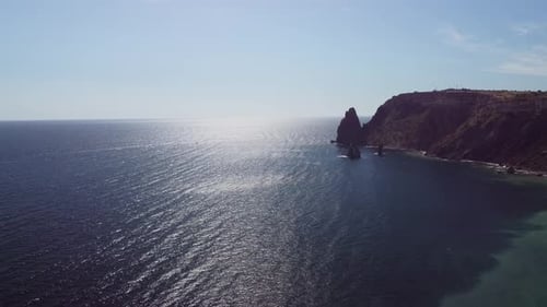 Luftbild von oben auf ruhiges azurblaues Meer und vulkanische Felsküsten