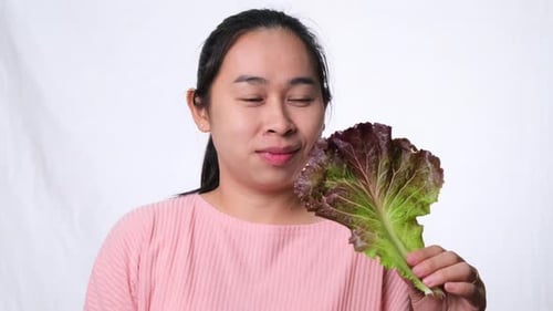 Healthy Asian woman with fresh salad showing thumbs up on white background in studio.
