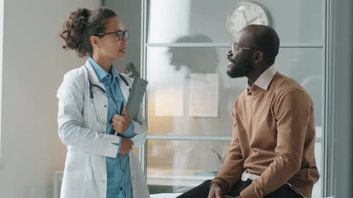 Portrait of Cheerful Female Doctor and African American Man in Clinic