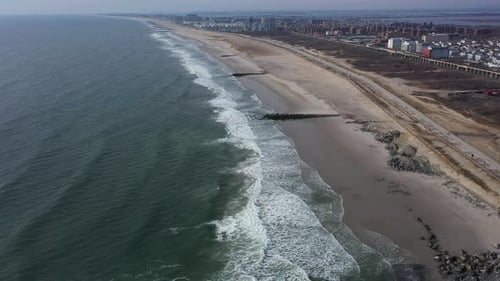 A drone view over an empty beach full of rocks on a hazy day. The camera dolly out over the water, a