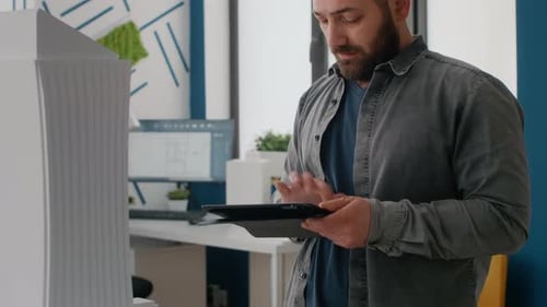 Nahaufnahme eines Architekten mit digitalem Tablet zum Entwerfen von Gebäudemodell und Layout im Büro