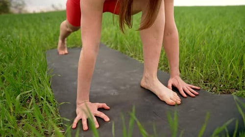 Young Woman Practicing in Handstand Plank Yoga Outdoors in Green Field