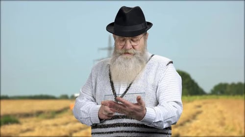 Senior Man Using a Futuristic Clear Tablet Outdoors
