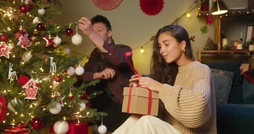 Couple Decorating Christmas Tree and Opening Gifts