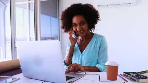 Young Woman Works on Laptop and Cellphone