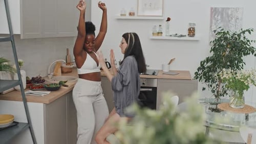 Two Women Dancing Together in Bright Kitchen
