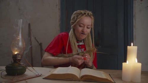 Woman Tying Straw Bundle at Table with Book