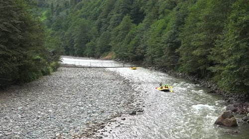 Two Yellow Inflatable Boats Rafting on the River in the Forest