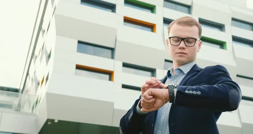 Young Adult Uses Smart Watch Outside Office Building