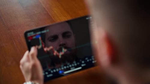 Man Holding Tablet Displaying Stock Market Chart
