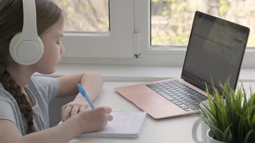 Focused School Girl Wearing Wireless Headphones Studying Online at Virtual Class with Teacher Tutor