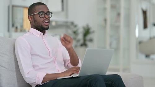 Young Adult Using Laptop on Gray Couch at Home