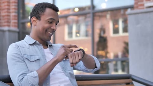 Young Adult Interacts With Smartwatch in Urban Setting