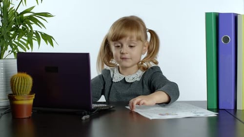 Child Doing Homework on Laptop Computer at Desk