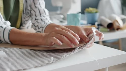 Closeup of Female Hands Sewing Clothes with Needle While Woman Working in Studio