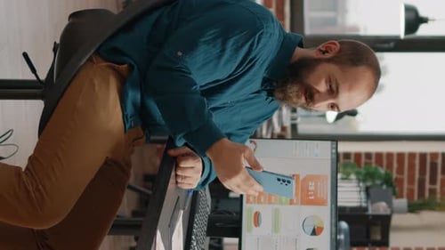 Man reviews data on phone in modern office