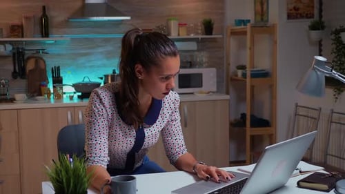 Tired Woman Working on Laptop in Kitchen