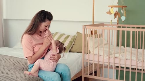 Mother Breastfeeding Baby Indoors by Crib