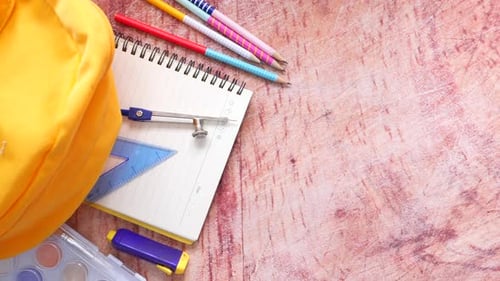 Top View of Yellow Backpack with Different Colorful Stationery on Table