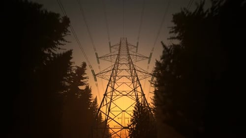 Toma en
bucle de torres eléctricas de alta tensión durante la puesta de sol. Cielo naranja. 4k