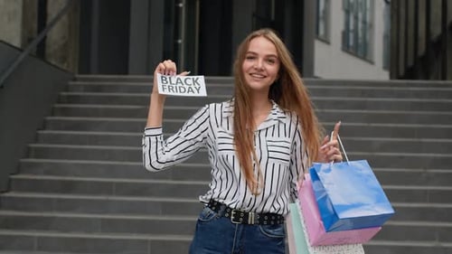 Smiling Woman with Black Friday Sign and Shopping Bags