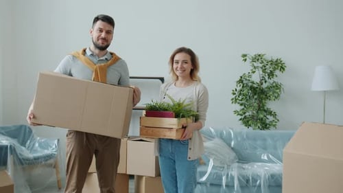 Porträt eines Mannes und einer Frau, die während des Umzugs Kisten halten und in die Kamera blicken