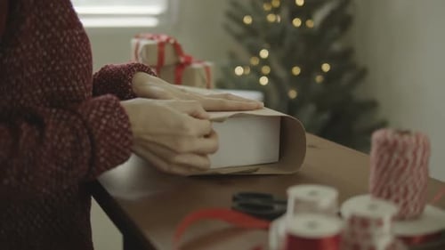 Woman Wrapping Christmas Gift at Home