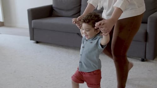 Adorable Infant Taking First Steps with Support
