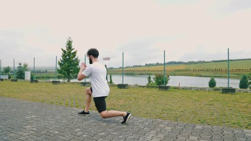 Athletic Man Doing Lunges by Lake Outdoors