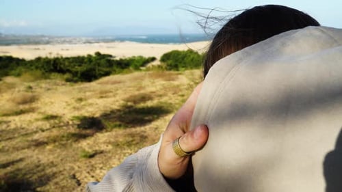 A Woman Pulls Down a Hoodie Looking at Scenic Landscape Across the Beach of Pan Rang in Vietnam on a