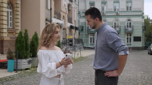 Young Woman Showing Phone to Man Outdoors
