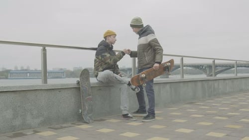 Young Adults Hanging Out with Skateboard by River