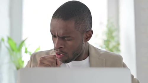 Close Up of African Man Coughing While Using Laptop