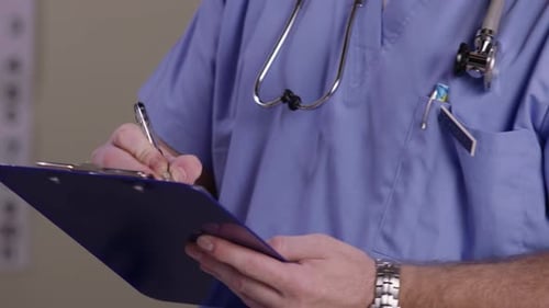 Medical Professional Writing on Clipboard in Clinic