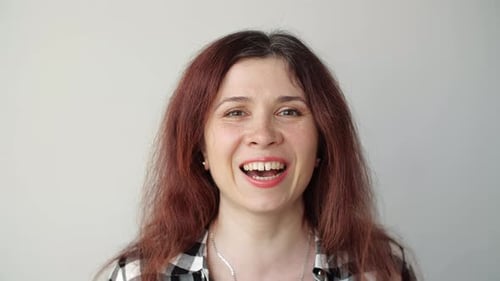 Smiling Woman with Reddish Hair against White Background