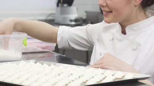 Woman Sprinkling Sugar on Meringue Cookies in Kitchen