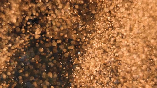 Goldene Partikel fließen mit geringer Schärfentiefe unter Wasser